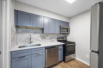 an empty kitchen with blue cabinets and stainless steel appliances
